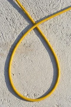 Yellow electric cable loop on textured plaster wall background Stock Photos