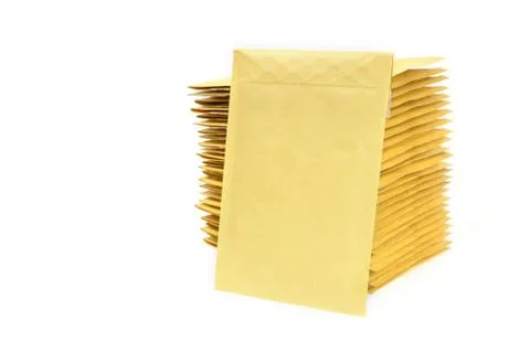 Yellow envelope leaning on a huge stack of bubble mailers. Stockfoto's