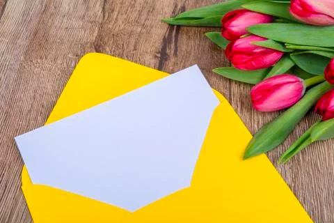 Yellow envelope with tulips on a table Stock Photos