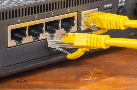 Yellow ethernet cable connected to a network router port close up. Stock Photos