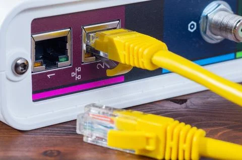 Yellow ethernet cable connected to a network router port close up. Stock Photos