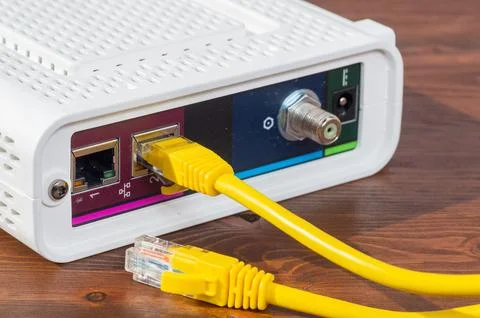 Yellow ethernet cable connected to a network router port close up. Stock Photos