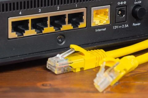 Yellow ethernet cable connected to a network router port close up. Stock Photos