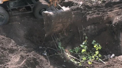 A yellow excavator at a construction site is digging the soil, close-up of th 動画素材 297210727