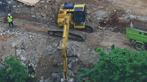 Yellow excavator digging deep into rocky soil at urban development construction 스톡 동영상 337989938