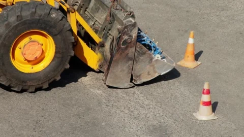 Yellow excavator loader bucket with drilling equipment on asphalt, close-up Stock Footage 317090142