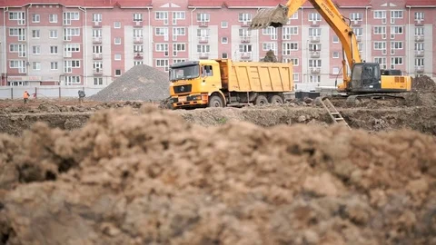 Yellow excavator loads clay using its big bucket Видео 78041294