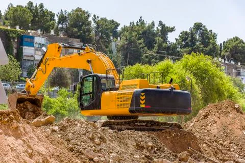 Yellow excavator machine with risen boom construction site Stock Photos