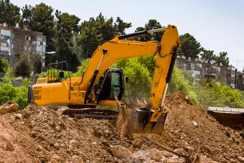 Yellow excavator machine with risen boom construction site Stock Photos