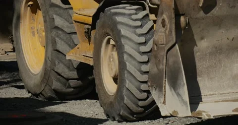 Yellow Excavator is Moving Wheels Close Up Scoop Worker's Legs Yellow Workwear Stock Footage 54332192