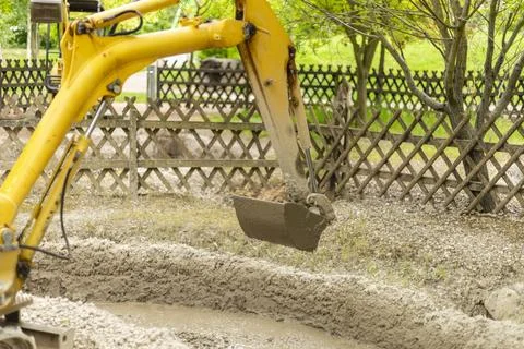 A yellow excavator performs earthmoving tasks in a construction zone surrou.. Stock Photos
