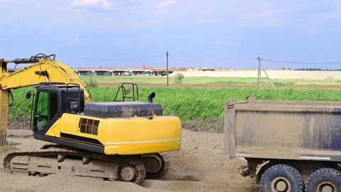 A yellow excavator performs leveling work on a road construction site and loa Stock Footage 202282494
