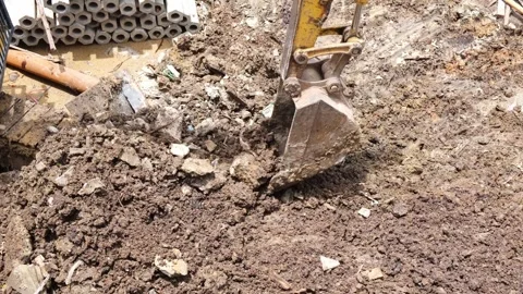 A yellow excavator is using its scoop to pick up soil debris and constructi.. Stock Footage 300072528