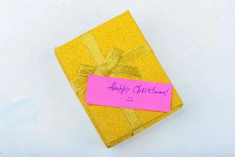 Yellow festive gift box with a note saying Happy Christmas. Stock Photos