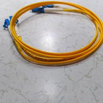 A yellow fiber optic patchcore cable lies on the floor 스톡 사진
