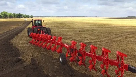 Yellow Field Flying Ower Big Tractor With Big Red Plow Stock Footage 73714670