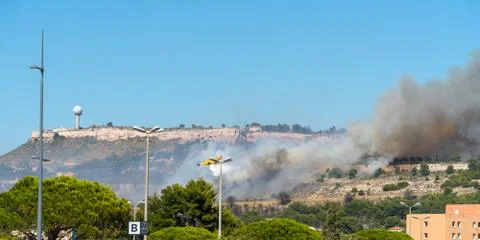 Yellow fire-fighting plane is throwing water on fire Stock Photos