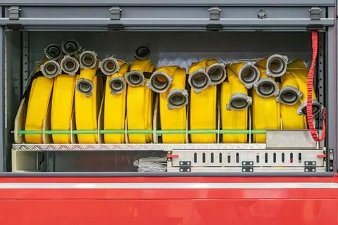 Yellow fire hoses in a green-padded, metal-barred compartment Indoor settin.. Stock Photos