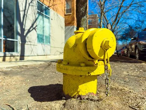 Yellow fire hydrant stands on the ground next to a building with clear wind.. Fotos Stock