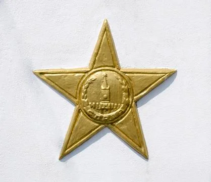 Yellow five-pointed star on a white wall. A symbol of victory. Stock Photos
