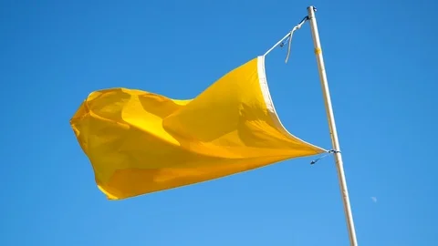 Yellow flag flying in the wind on the beach against blue sky. Slow motion. HD Stock Footage 119824465