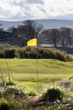 A yellow flag is on a golf course Stock Photos