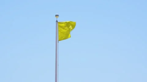 Yellow Flag Warning Waving Against Blue Sky. Signaling Hazardous Swimming C.. Stock Footage 336922190