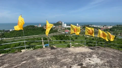 Yellow flags flapping on top of rocky hill sunny day landscape blue sky ocean Stock Footage 252161276
