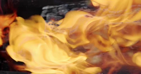 The yellow flames of the fire slowly lick the burning charred logs. Stock Footage 144985538