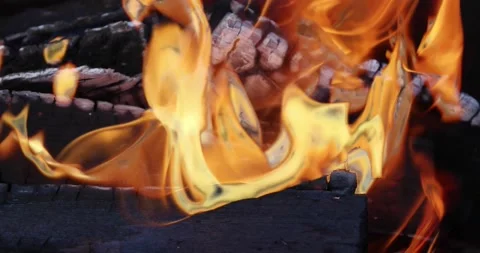 The yellow flames of the fire slowly lick the burning charred logs. Stock Footage 144985591