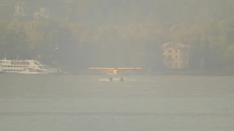 Yellow floatplane lands on the water in Lake como Stock Footage 127823779