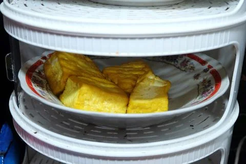 Yellow fried tofu served on a patterned ceramic plate. The plate is placed .. Stock Photos