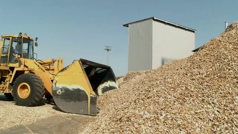 Yellow front loader with bucket down scooping wood chips for biofuel Stock Footage 71165136