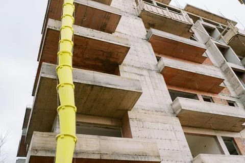 Yellow garbage pipe is attached to the outer wall of a multi-storey building 스톡 사진