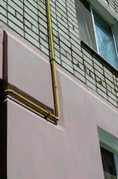Yellow gas pipe viewed on the outer brick wall of residential building. Stock Photos