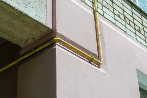 Yellow gas pipe viewed on the outer brick wall of residential building. Stock Photos