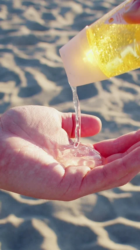 Yellow gel is squeezed out on a hand on a sandy beach 스톡 동영상 237705774