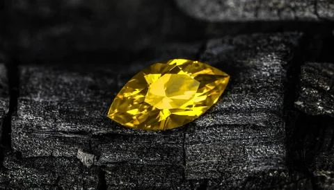 A yellow gemstone is on a black surface Stock Photos