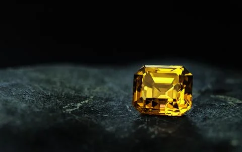 A yellow gemstone sits on a dark surface Stock Photos
