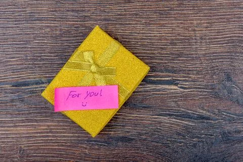 Yellow gift box with handwritten note For you. Stock Photos