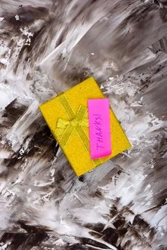Yellow gift box with note Thanks. Stock Photos