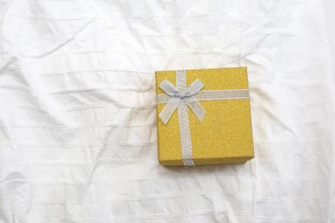Yellow Gift box. Present box for Holidays on white sheets of a bed Valentine's Stock Photos