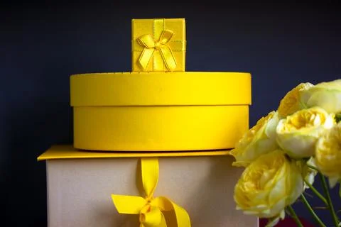 Yellow gift boxes stacked black background, Austin roses bouquet greetings card Stock Photos