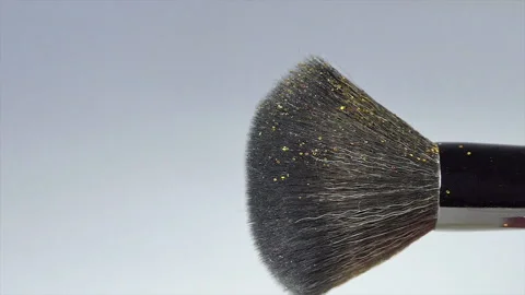 Yellow glitter falls on a makeup brush, slow motion on a white background Stock Footage 227960651