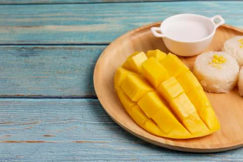 Yellow half  mango with small fork. Mango fruit cubes on the Blue wooden tabl Stock Photos