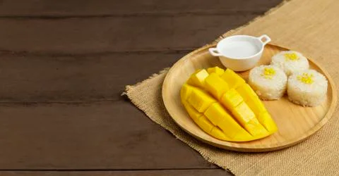 Yellow half  mango with small fork. Mango fruit cubes on the wooden table. Tr 스톡 사진
