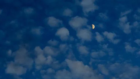 Yellow half moon in the clouds at dusk Stock Photos