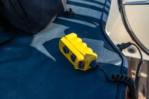 Yellow handheld control device on blue cushioned boat seat Photos