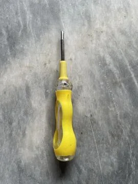 Yellow Handled Screwdriver on a Concrete Surface Stock Photos