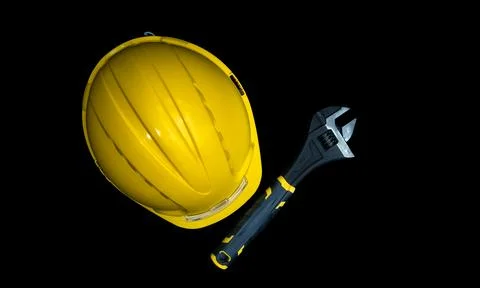 Yellow hard hat and adjustable wrench on black background Stock Photos